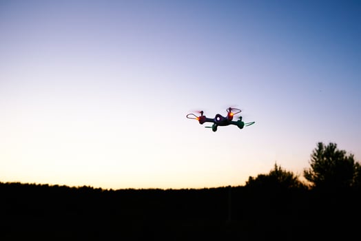 Toy drone quad copter against sunset sky photo