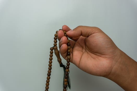 hand holding wooden tasbih beads isolated. islamic prayer beads. moslem praying concept photo