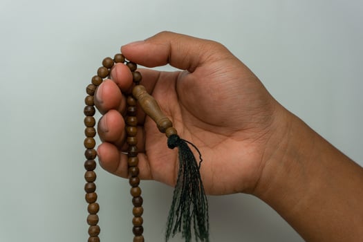 hand holding wooden tasbih beads isolated. islamic prayer beads. moslem praying concept photo