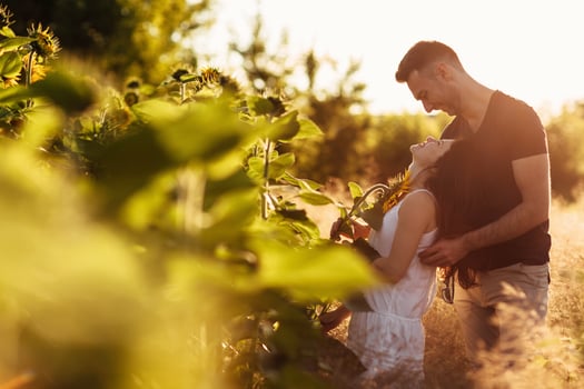 Beautiful couple having fun in sunflowers field. A man and a woman in love walk in a field with sunflowers, a man hugs a woman. selective focus photo