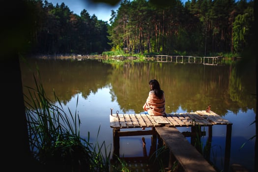 A young girl is sitting on an old bridge. Nature photo