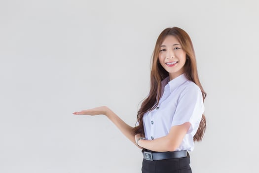 Portrait of an adult Thai student in university student uniform. Asian beautiful girl standing to present something confidently on white background. photo