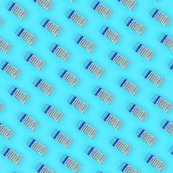 Small stainless steel graters lies on a pastel colored paper. Kitchen accessories. Tools for cooking. Flat lay top view photo
