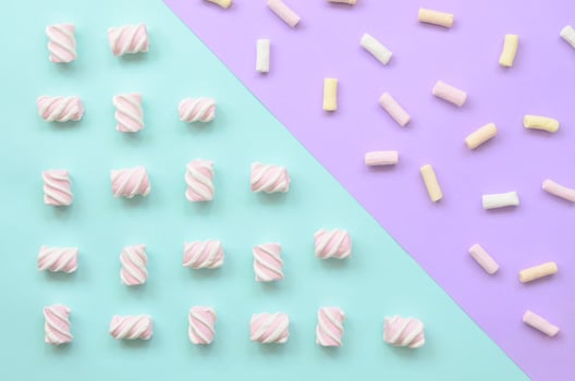 Colorful marshmallow laid out on violet and blue paper background. pastel creative textured pattern. minimal photo