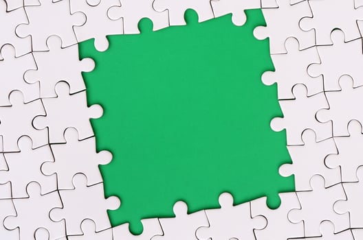 Framing in the form of a rectangle, made of a white jigsaw puzzle around the green space photo