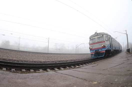 The Ukrainian suburban train rushes along the railway in a misty morning. Fisheye photo with increased distortion