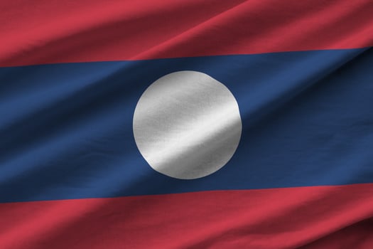 Laos flag with big folds waving close up under the studio light indoors. The official symbols and colors in banner photo