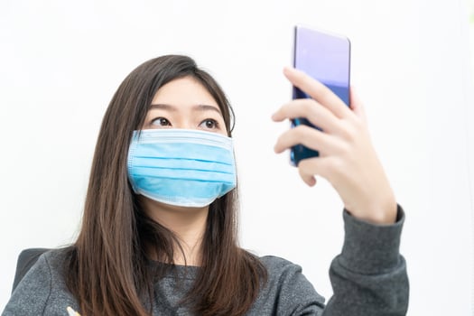 Woman long hair wearing protective mask holding and using mobile phone photo