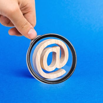 A magnifying glass looks at a email icon on blue background. internet correspondence. Contacts for business. Business tools. Internet and global communication, digitalization of economy. at commercial photo