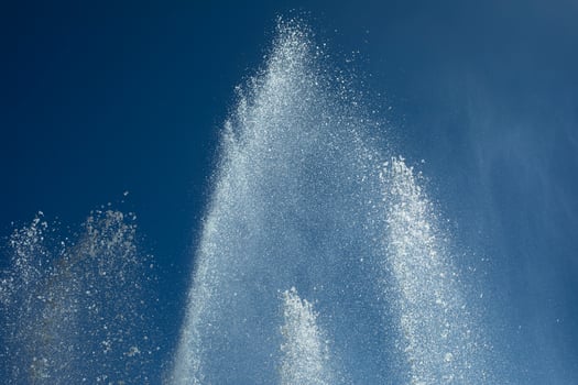 Jets of water against sky. Fountain in city. Details of fountain on street. photo