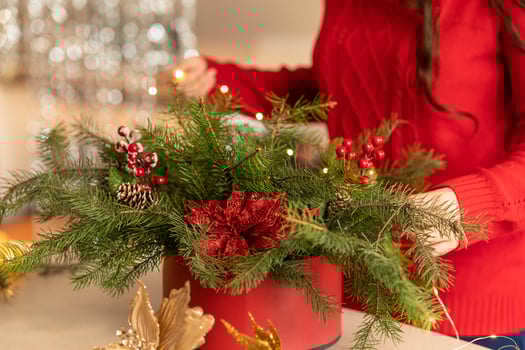 girl collects a Christmas bouquet of fir branches, flowers and Christmas tree decorations photo