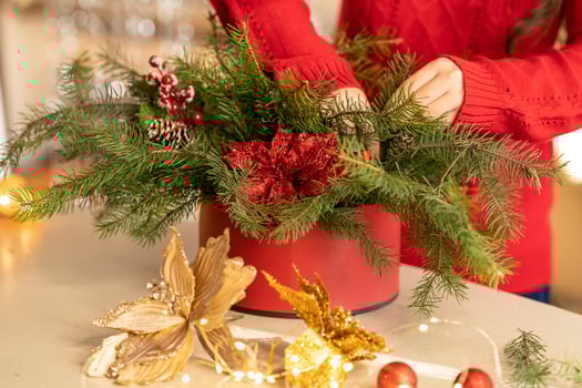 girl collects a Christmas bouquet of fir branches, flowers and Christmas tree decorations photo