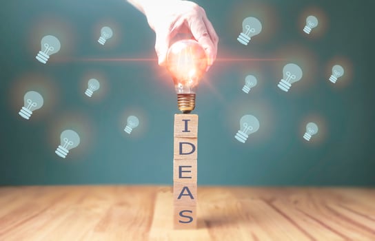 hand touching on light bulb on wood block with Word Ideas, new idea concept with innovation and inspiration, innovative technology in science and communication concept. photo