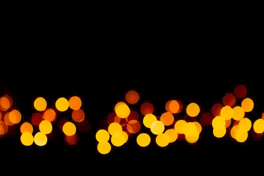 Holiday glowing gold backdrop. defocused and blurred many round yellow light on Christmas black background photo