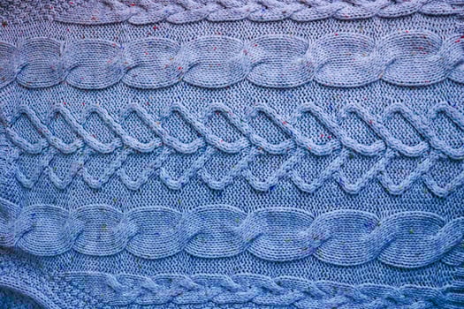 Beautiful texture of a soft warm natural sweater with a knitted pattern of threads. The background photo