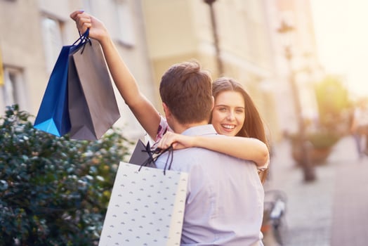 Portrait of happy couple with shopping bags in city smiling and huging. photo