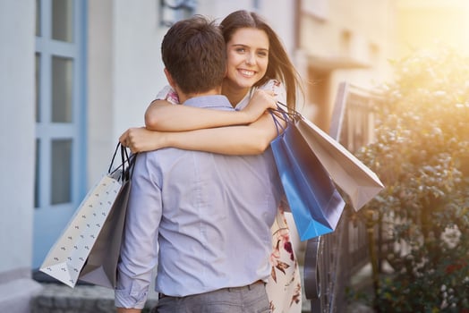 Portrait of happy couple with shopping bags in city smiling and huging. photo