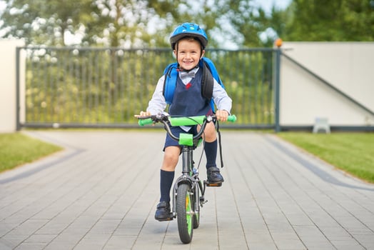 School boy in safety helmet riding bike with backpack photo