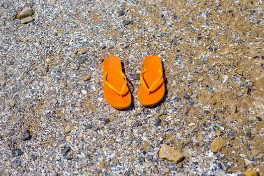 travel background with a pair of orange flip-flops in the sand photo