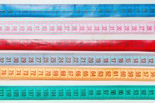 Close up of a group of colorful measure tapes lying in rows as a background. Diet concept on wooden background photo
