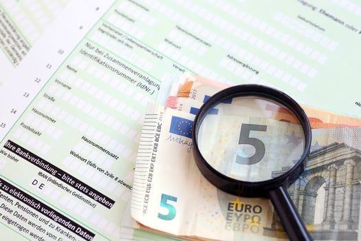 German income tax return form with magnifying glass and european euro money bills lies on accountant table close up. Taxpayers in Germany using euro currency to pay taxes photo