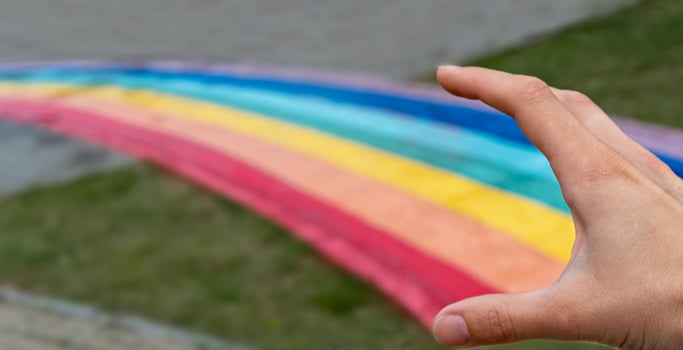 Human hand releasing a rainbow path on city street, copy space, love, freedom and friendship, abstract photo