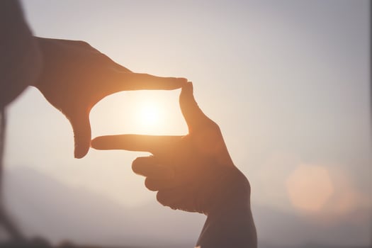 Planning and vision concept of new year's start, woman hand making frame gesture find focus at sunset, woman looking for perspective to capture the meaning of a clear upcoming target. photo