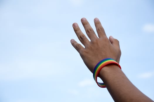 Rainbow wristband wearing in hand of young asian gay to show and represent gender diversity, to respect human rights in alternative sex, to stop punishing homosexuals in some religions photo