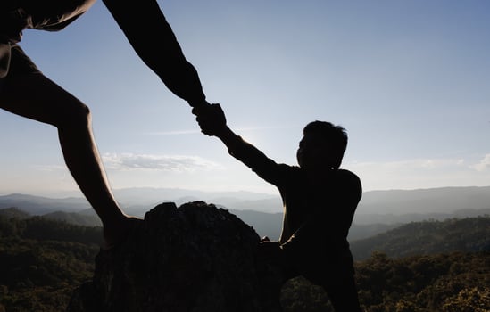 Silhouette of hiker helping each other hike up a mountain at sunset. People helping and, team work concept. photo