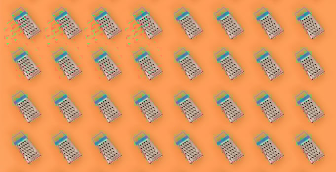 Small stainless steel graters lies on a pastel colored paper. Kitchen accessories. Tools for cooking. Flat lay top view photo