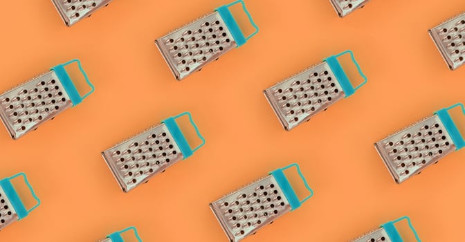 Small stainless steel graters lies on a pastel colored paper. Kitchen accessories. Tools for cooking. Flat lay top view photo