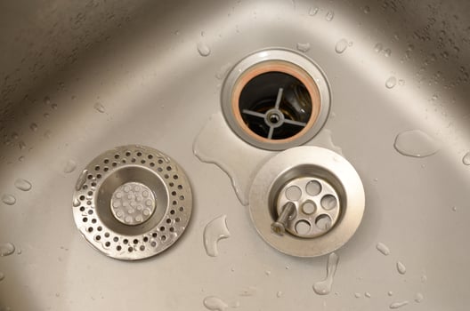 Silvery kitchen sink with a disassembled protective filter during the repair process photo