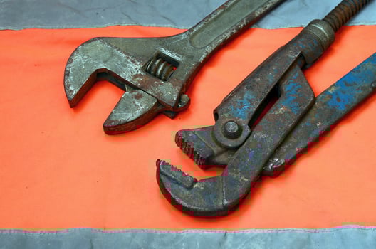 Adjustable and pipe wrenches against the background of an orange signal worker shirt photo
