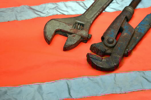 Adjustable and pipe wrenches against the background of an orange signal worker shirt photo