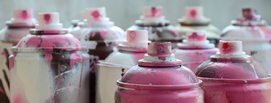 A lot of dirty and used aerosol cans of bright pink paint. Macro photograph with shallow depth of field. Selective focus on the spray nozzle photo