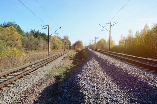 Autumn industrial landscape. Railway receding into the distance among green and yellow autumn trees photo
