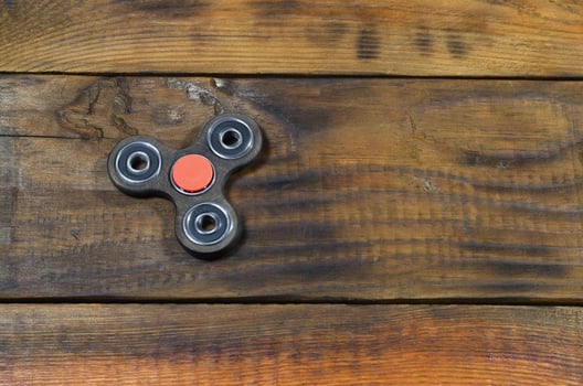A rare handmade wooden fidget spinner lies on a brown wooden background surface. Trendy stress relieving toy photo