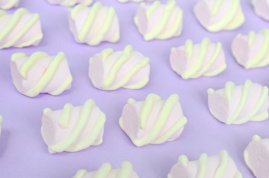 Colorful marshmallow laid out on violet paper background. pastel creative textured pattern. Perspective macro shot photo