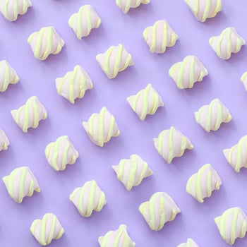 Colorful marshmallow laid out on violet paper background. pastel creative textured pattern. minimal photo