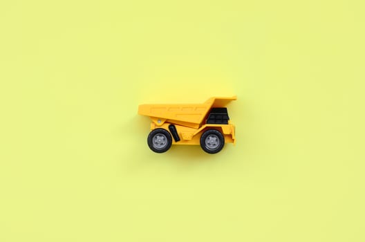 Small yellow toy truck on texture background of fashion pastel yellow color paper in minimal concept photo