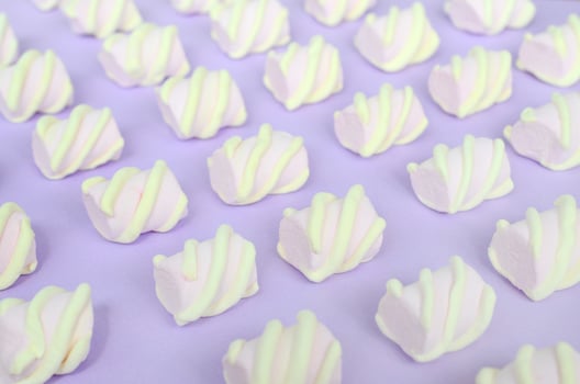 Colorful marshmallow laid out on violet paper background. pastel creative textured pattern. Perspective macro shot photo