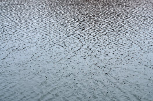 The texture of the water in the river under the influence of wind. A lot of shallow waves on the water surface photo