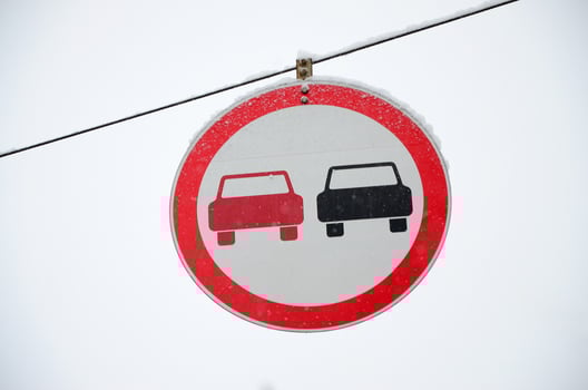 Road sign. Overtaking is prohibited. The sign prohibits overtaking all vehicles on the road section. A red and black car is depicted in a framed red circle photo