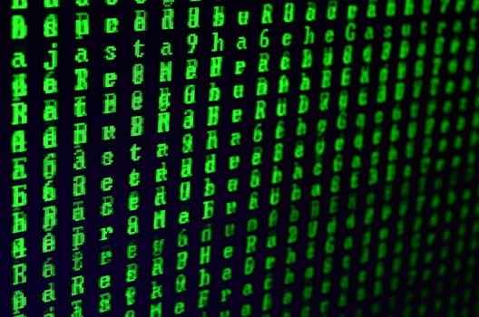 Macro shot of a glitch on the monitor of an office computer. The concept of introducing a virus into a personal data keeper. Stream of random green symbols on a black background photo