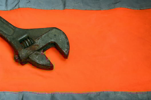 Adjustable wrench against the background of an orange signal worker shirt photo