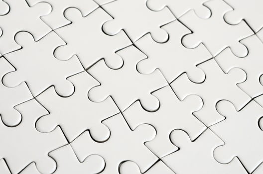 Close up of a white jigsaw puzzle in assembled state in perspective. Many components of a large whole mosaic are united photo