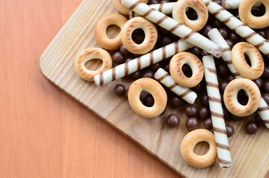 Crispy tubules, chocolate melting balls and bagels lie on a wooden surface. Mix of various sweets photo