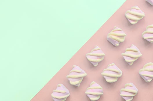Colorful marshmallow laid out on turquoise and pink paper background photo