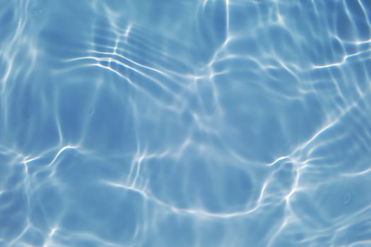 Defocus blurred transparent blue colored clear calm water surface texture with splashes and bubbles. Trendy abstract nature background. Water waves in sunlight with copy space. Blue watercolor shining photo