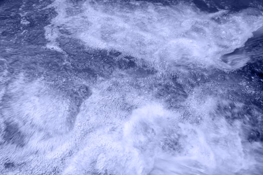 Defocus blurred transparent blue colored clear calm water surface texture with splashes and bubbles. Trendy abstract nature background. Water waves in sunlight with copy space. Blue watercolor shining photo